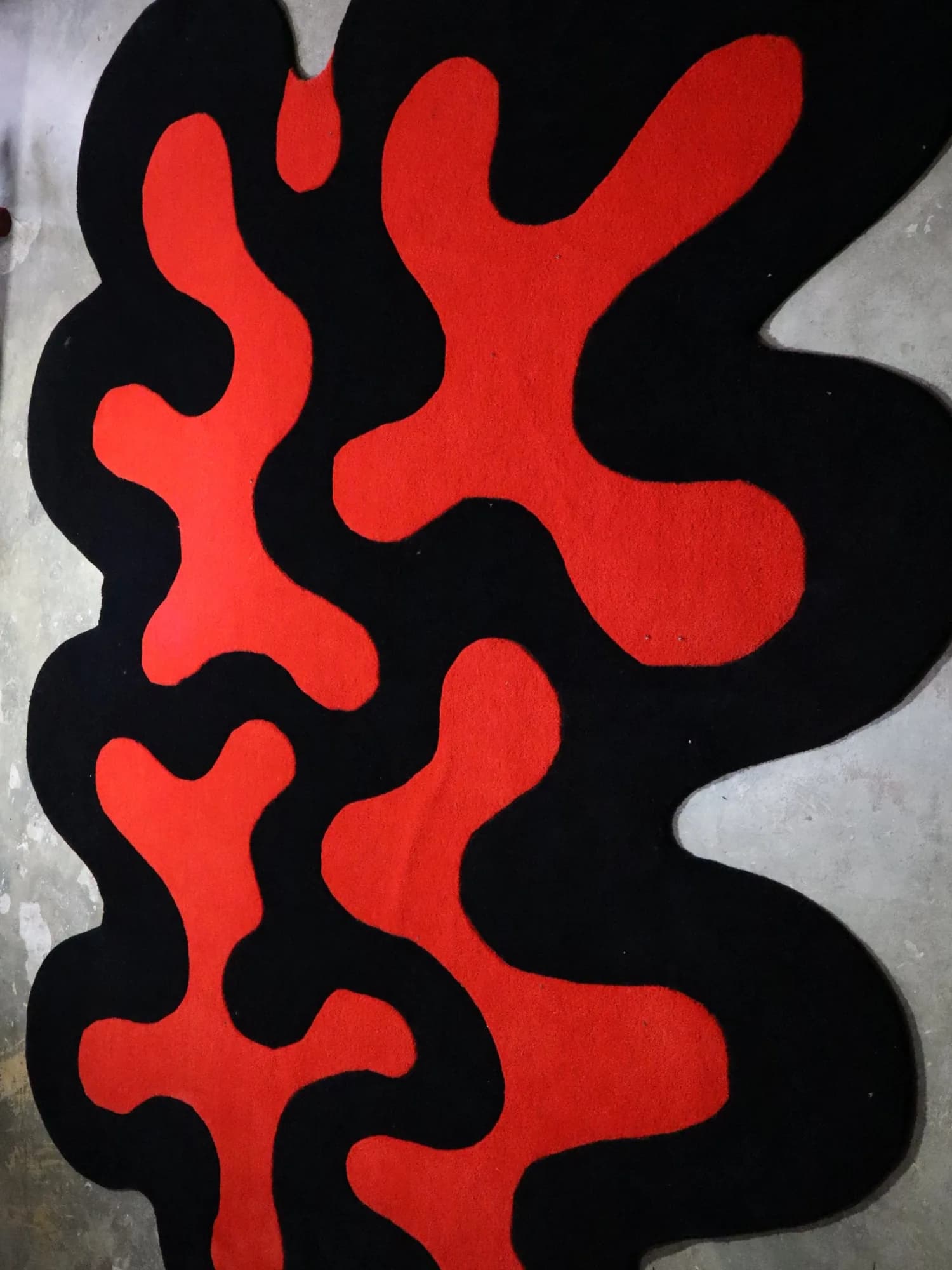 Agni carpet seen from above: red organic forms on a black free-form ground